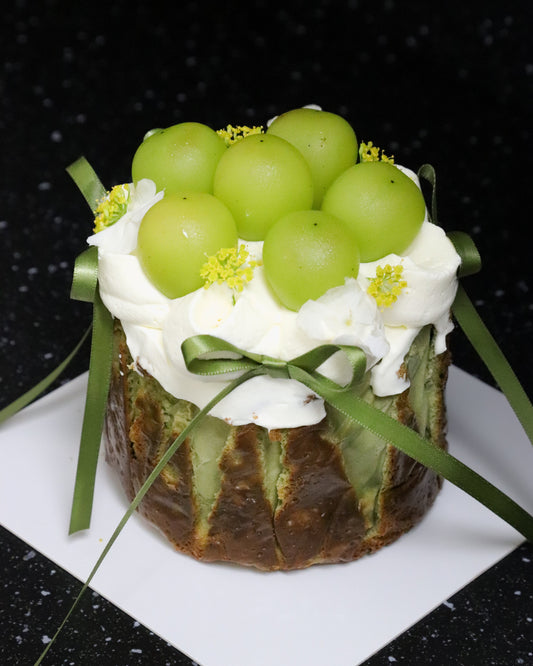 cheesecake with white fresh cream, green grapes, yellow flowers and green ribbon bows on a black background